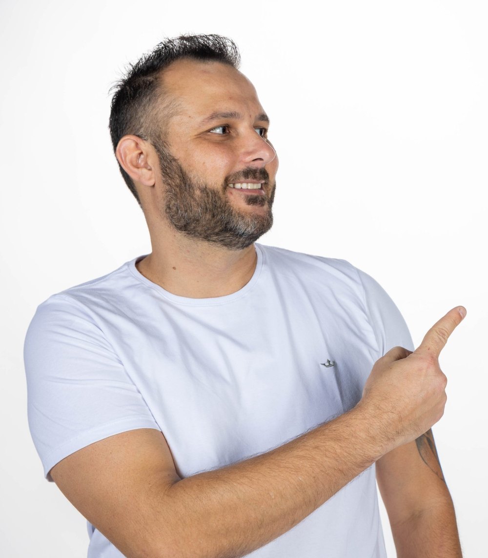 João Marcel Camargo de camiseta branca, sorrindo e apontando